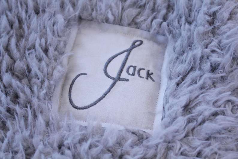 May include: A grey fluffy blanket with a white tag that says "Jack" in cursive.