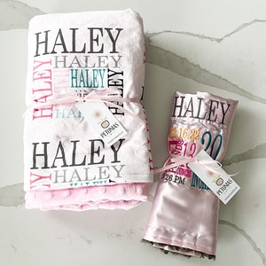 Puede incluir: Dos mantas de beb&eacute; rosas con el nombre "Haley" bordado. Una manta es blanca con lunares rosas y la otra es de sat&eacute;n con ribete de piel marr&oacute;n. Ambas mantas tienen una etiqueta con el nombre "Petunias" en ellas.