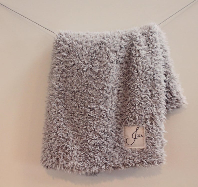 May include: A grey fluffy blanket with a white label that says "Jack" on it.