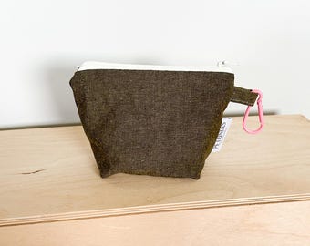 May include: A small, dark green zippered pouch with a white trim and a pink clip. The pouch is made of a textured fabric and has a small label that says "PETUNIAS".