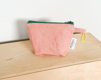 May include: A small pink zippered pouch with a green zipper and a yellow clip. The pouch has a white label with the text "PETUNIAS" and "Dye-Sublimated".