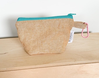 May include: A small, beige zippered pouch with a teal zipper and a pink carabiner clip. The pouch has a label that reads "PELUNIAS" and "handmade".