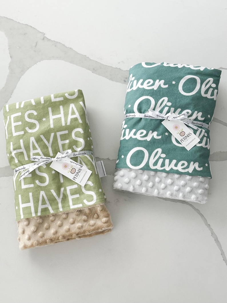 Puede incluir: Dos mantas para beb&eacute; personalizadas, una verde con estrellas blancas y el nombre "Oliver" y otra verde con estrellas blancas y el nombre "Hayes". Ambas mantas tienen un respaldo suave de minky.