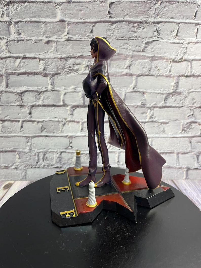K&ouml;nnte beinhalten: Figur einer Figur in einem dunkelvioletten Outfit mit langem Umhang, die auf einer schwarz-roten Basis steht. Die Figur hat eine Kapuze und goldene Akzente. Die Basis hat schach&auml;hnliche Teile.