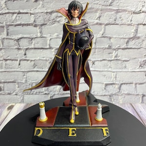 Puede incluir: Figura detallada de un personaje con un atuendo morado y dorado con una larga capa roja. La figura sostiene un casco negro y se encuentra sobre una base con las letras "D", "E" y "F". Dos piezas de ajedrez están en la base.