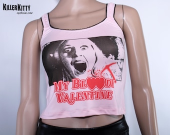 May include: Pink tank top with a black lace trim and a graphic print of a woman with a bloody heart and the text "My Bloody Valentine".