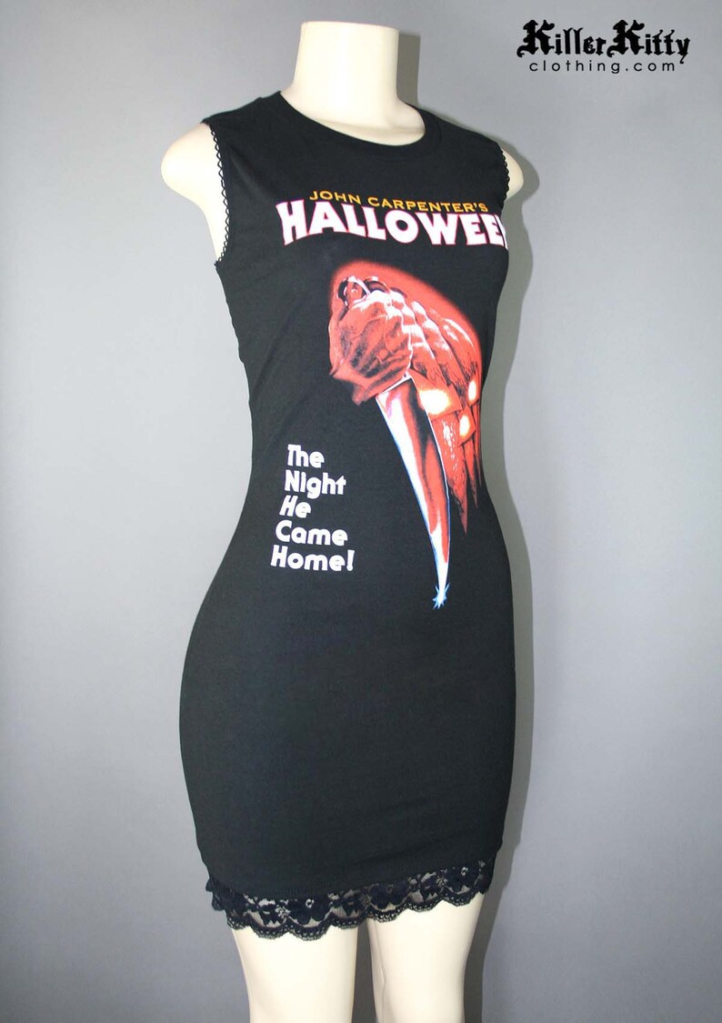 Sleeveless dress upcycled from a Halloween shirt, modified for a flattering female fit and style. It has a high neck with black, picot elastic trimming the arms. The hem is trimmed with peek-a-boo black lace.