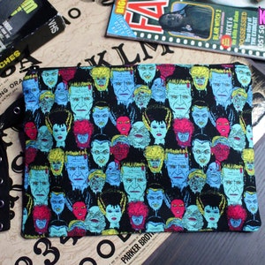 Custom-made Universal Horror Monsters pouch. All over print of The Bride of Frankenstein, Frankenstein, Dracula, Wolfman, The Mummy and Creature from the Black Lagoon. Polka dot lining, zipper closure and grommet strap on the side.