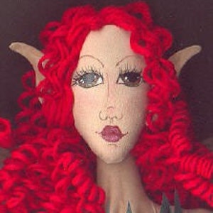 Pu&ograve; includere: Una bambola fatta a mano con capelli rossi ricci, orecchie a punta e un viso dipinto. La bambola ha occhi marroni, una bocca rosa e un incarnato chiaro.