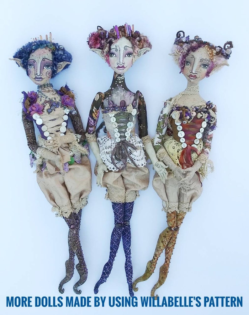 May include: Three handmade fabric dolls with whimsical features, wearing elaborate outfits with lace and buttons. The dolls have unique hairstyles and painted faces.  The dolls are standing on a white background.  "MORE DOLLS MADE BY USING WILLABELLE'S PATTERN" is written at the bottom of the image.
