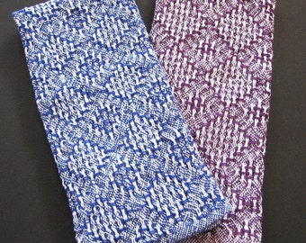 May include: Two kitchen towels, one blue and white, the other purple and white, with a woven pattern.