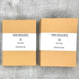 May include: Three brown paper boxes with white labels. The labels read "MINI ENVELOPES" with the number of envelopes in each box: 10, 25, and 50. The labels also say "PEEL & SEAL" and "ATOMICKNITTING".