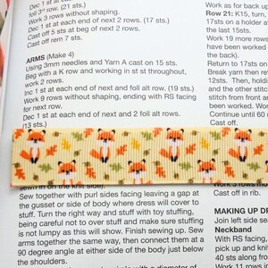 May include: A close-up of a yellow fabric with a pattern of orange foxes and brown leaves. The fabric is a ribbon with a white background. The text "Work as for back up Row 21: K15, turn, 17sts on a holder at the last 15sts. Work 19 more rows have been worked the back). Return to 17sts on Break yarn then ret 12sts. Then, holdi and the other stitc stitch from front an been worked. Wor Continue until 60 Cast off." is printed on the fabric.