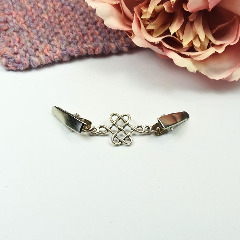 Silver celtic eternity knot cardigan sweater clip on a white background.