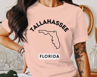 May include: A pink t-shirt with a black outline of the state of Florida and the text "Tallahassee, Florida".