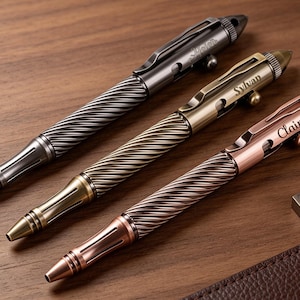 May include: Three metal pens with a twisted spiral grip and a bolt-action mechanism. The pens are finished in gunmetal, brass, and copper tones. Each pen features a personalized name engraved on the clip area: Helen, Sylvan, and Claire.