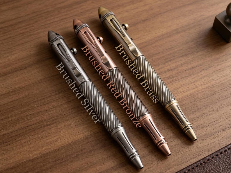 May include: Three bolt-action pens with a textured, spiraled grip and a smooth upper barrel. The pens are labeled Brushed Silver, Brushed Red Bronze, and Brushed Brass. Each pen features a metal pocket clip, a bolt-action mechanism, and a pointed tip.