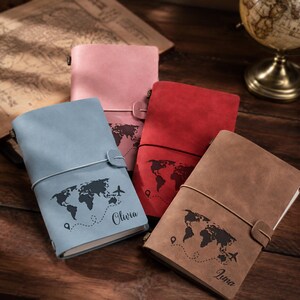 May include: Four rectangular journals with matte covers in light blue, pink, red, and brown. Each cover features a dark world map silhouette, a dashed flight path, a location pin, an airplane icon, and a personalized name in cursive script.