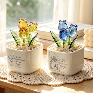 May include: Two square white ceramic planters filled with small stones and glass tulips. The left planter features a yellow balloon, a bear illustration, and text reading You are smarter and braver than you believe. The right features a bear and tree illustration with text reading Thank you for helping me grow.