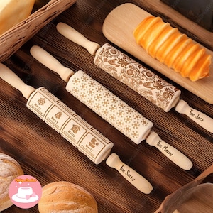 May include: Three wooden rolling pins with engraved designs. The rolling pins are decorated with snowflakes, a Christmas tree, a house, and a snowman. The handles are labelled "The Sally", "The Marry", and "The Jack".