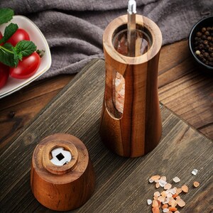 May include: A wooden salt grinder with a clear glass section to view the pink Himalayan salt inside. The grinder has a wooden top with a small hole for grinding the salt.