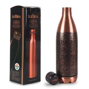 May include: A copper water bottle with an ornate floral pattern, a black cap, and a matching box. The bottle is made of pure copper and has a stylish design. The box features the brand name "SUVIRA" and the words "PURE COPPER BOTTLE".