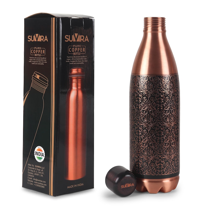 Puede incluir: Una botella de agua de cobre con un intrincado dise&ntilde;o floral, una tapa negra y una caja a juego. La botella est&aacute; hecha de cobre puro y tiene un dise&ntilde;o elegante. La caja presenta la marca "SUVIRA" y las palabras "PURE COPPER BOTTLE".