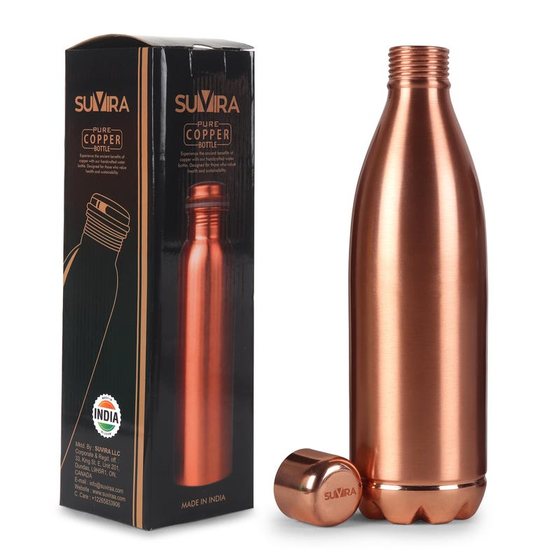 Puede incluir: Una botella de agua de color cobre con su tap&oacute;n, junto a su caja negra. La caja muestra la marca "SUMIRA" y las palabras "PURE COPPER BOTTLE". La botella est&aacute; hecha en India.