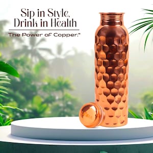 Könnte beinhalten: Eine kupferfarbene Wasserflasche mit strukturierter Oberfläche und passendem Deckel. Der Text "Sip in Style, Drink in Health" und "The Power of Copper" ist zu sehen. Die Flasche steht auf einer weißen Plattform.