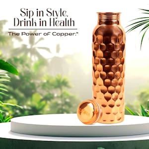 Puede incluir: Una botella de agua de cobre con textura martillada y tapa de rosca a juego. El texto "Sip in Style, Drink in Health" y "The Power of Copper." es visible. La botella tiene un cuerpo cilíndrico con cuello estrecho y acabado metálico.