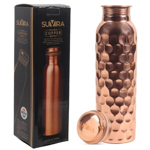 Puede incluir: Una botella de agua de cobre con una superficie texturizada y con hoyuelos, una tapa a juego y una caja negra. La caja presenta el texto "SUVIRA PURE COPPER BOTTLE" y una imagen de la botella. La botella est&aacute; hecha en India.