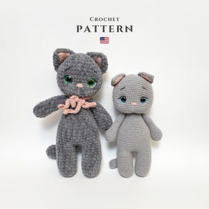 Könnte beinhalten: Zwei handgefertigte Häkelkatzenpuppen in Grautönen. Die größere Katze hat grüne Augen und einen rosa Schal, während die kleinere blaue Augen hat. Der Text "CROCHET PATTERN" steht oben, darunter die amerikanische Flagge.