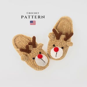 May include: A pair of handmade, tan crochet reindeer slippers. Each slipper features brown antlers, a white face with a red nose, and black eyes. The text "CROCHET PATTERN" is above the slippers, with the American flag below.