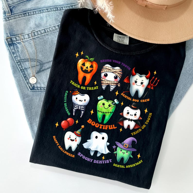 May include: A black t-shirt featuring a graphic of nine cartoon teeth dressed in Halloween costumes, including a pumpkin, mummy, devil, skeleton, Frankenstein, vampire, party guest, ghost, and witch, with text including Trick or Treat and Bootiful.