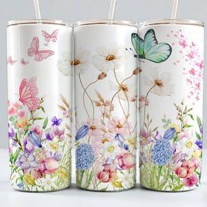 May include: Three white stainless steel tumblers with floral and butterfly designs. The tumblers feature watercolor illustrations of pink and purple flowers, butterflies, and greenery. Each tumbler has a clear straw.