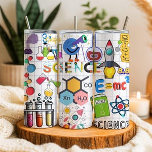 Könnte beinhalten: Drei Edelstahlbecher mit wissenschaftlichen Grafiken. Jeder Becher hat einen weißen Hintergrund mit farbenfrohen Illustrationen von Bechern, Raketen und wissenschaftlichen Formeln. Das Wort "SCIENCE" ist prominent dargestellt.