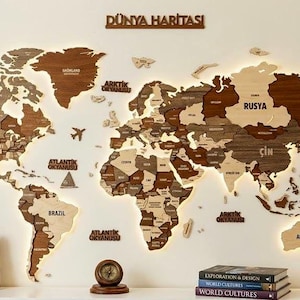 Puede incluir: Un mapa del mundo de madera con bordes iluminados, que muestra los contornos de los países en varios tonos de marrón. El mapa incluye el texto "DÜNYA HARİTASI" y está acompañado de libros, una brújula y diarios encuadernados en cuero. Decoración.