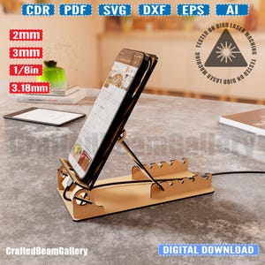 Puede incluir: Un soporte de tel&eacute;fono de madera con un dise&ntilde;o de corte. El soporte est&aacute; dise&ntilde;ado para sostener un tel&eacute;fono en posici&oacute;n vertical y tiene una ranura para cables de carga. El soporte est&aacute; hecho de madera marr&oacute;n claro y est&aacute; sentado en una mesa.