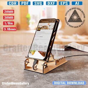 Puede incluir: Un soporte de tel&eacute;fono de madera con una ranura para cables de carga. El soporte est&aacute; dise&ntilde;ado para sostener un tel&eacute;fono inteligente en posici&oacute;n vertical. El soporte est&aacute; hecho de madera marr&oacute;n claro y tiene un dise&ntilde;o simple. El soporte se muestra con un tel&eacute;fono inteligente en &eacute;l, mostrando un sitio web en la pantalla. El texto "CraftedBeamGallery" es visible en la parte inferior de la imagen.