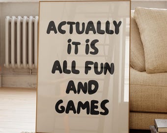 Könnte beinhalten: Ein gerahmtes Poster mit dem Text "ACTUALLY IT IS ALL FUN AND GAMES" in schwarzen Buchstaben. Das Poster befindet sich in einem hellfarbigen Rahmen und steht vor einem Fenster und einem beigen Sofa.