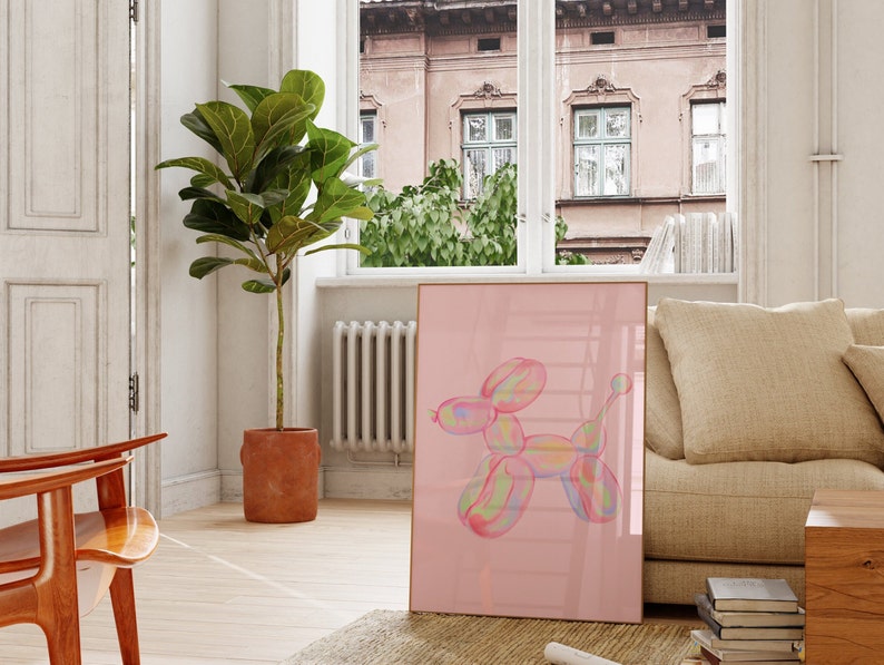 May include: A framed print of a colorful balloon animal shaped like a dog on a pink background. The print is hanging on a wall in a living room.