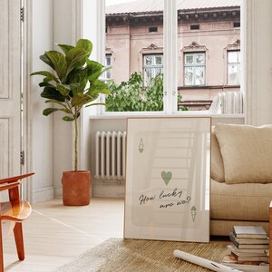 Puede incluir: Una impresi&oacute;n enmarcada de una carta de juego con un coraz&oacute;n verde y el texto "How lucky are we?" colgada en una pared blanca en una sala de estar. La impresi&oacute;n est&aacute; enmarcada en un marco dorado.