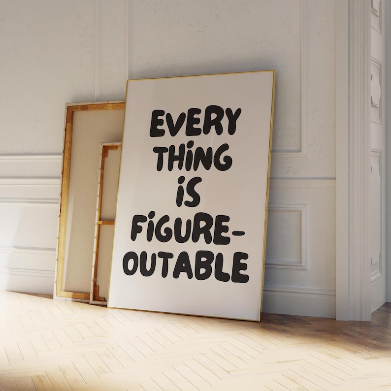 Puede incluir: Una impresi&oacute;n art&iacute;stica enmarcada con el texto "EVERYTHING IS FIGURE-OUTABLE" en letras negras en negrita. La impresi&oacute;n est&aacute; apoyada contra una pared blanca, junto a un lienzo con un marco dorado. La obra de arte se exhibe sobre un suelo de madera clara.