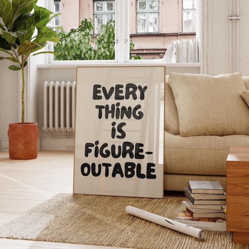 Puede incluir: Un p&oacute;ster enmarcado con el texto "EVERYTHING IS FIGURE-OUTABLE" en letras negras en negrita. El p&oacute;ster est&aacute; apoyado contra una pared en una habitaci&oacute;n con una combinaci&oacute;n de colores neutros, un sof&aacute; beige y una alfombra tejida.