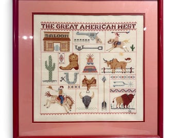 Könnte beinhalten: Ein gerahmter Kreuzstich-Sampler mit dem Titel THE GREAT AMERICAN WEST, der verschiedene Motive zeigt, darunter einen Saloon, einen Revolver, einen Cowboy auf einem Pferd, einen Kaktus, einen Stiefel, ein Tipi, ein Longhorn, ein Hufeisen, einen Sattel, einen Schädel, einen Pfeil und einen Büffel.