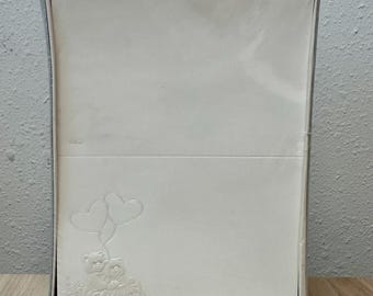 Könnte beinhalten: Ein Schachtelset mit weißem Briefpapier. Das Briefpapier zeigt geprägte Bilder von zwei Teddybären, die herzförmige Luftballons halten. Das Set ist in eine transparente Kunststofffolie und einen silberfarbenen Rahmen gehüllt.