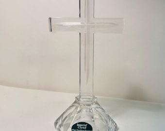 Könnte beinhalten: Ein klares Kreuz aus 24% Bleikristall auf einem facettierten, sechseckigen Sockel. Das Kreuz weist ein mittiges Ätzdesign auf. Ein grüner ovaler Aufkleber auf dem Sockel trägt die Aufschrift: Imperial Crystal, Fine European Designs, 24% Lead Crystal, Made in Poland.