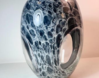 Könnte beinhalten: Eine mundgeblasene Glasvase in ovaler Form mit einer glatten, polierten Oberfläche. Das Glas weist ein marmoriertes Muster aus tief dunkelblauen und weißen Wirbeln auf, das eine komplexe, organische Textur auf dem gesamten Körper erzeugt.