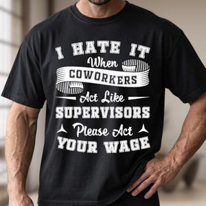 Puede incluir: Una camiseta negra de manga corta con texto blanco que dice I HATE IT When COWORKERS Act Like SUPERVISORS Please Act YOUR WAGE. El diseño incluye un gráfico de pancarta detrás de la palabra COWORKERS y pequeños acentos triangulares.
