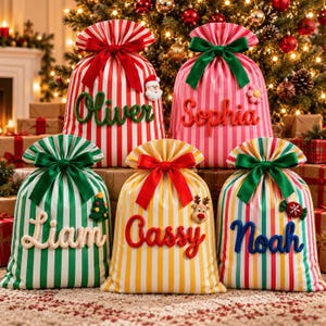 Può includere: Cinque sacchi regalo natalizi in tessuto con strisce verticali rosse, rosa, verdi, gialle e multicolori. Ogni sacco presenta un grande fiocco in raso sulla parte superiore e un nome personalizzato in lettere testurizzate con piccole decorazioni natalizie.